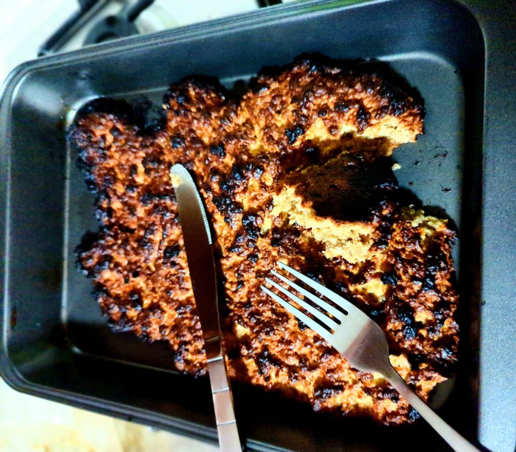A crispy, crunchy looking flapjack just about fitting into a baking dish that's supposed to be banana bread.